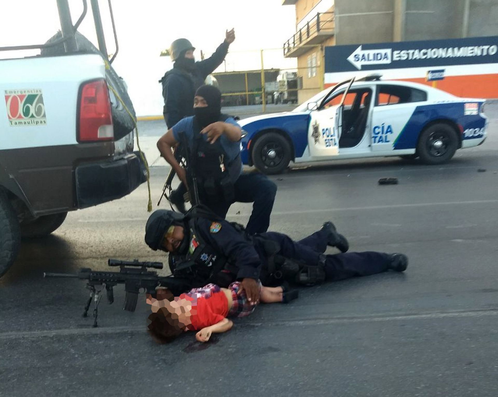 Policías protegiendo a un niño en el área de un enfrentamiento entre fuerzas de seguridad y grupos armados en Nuevo Laredo 