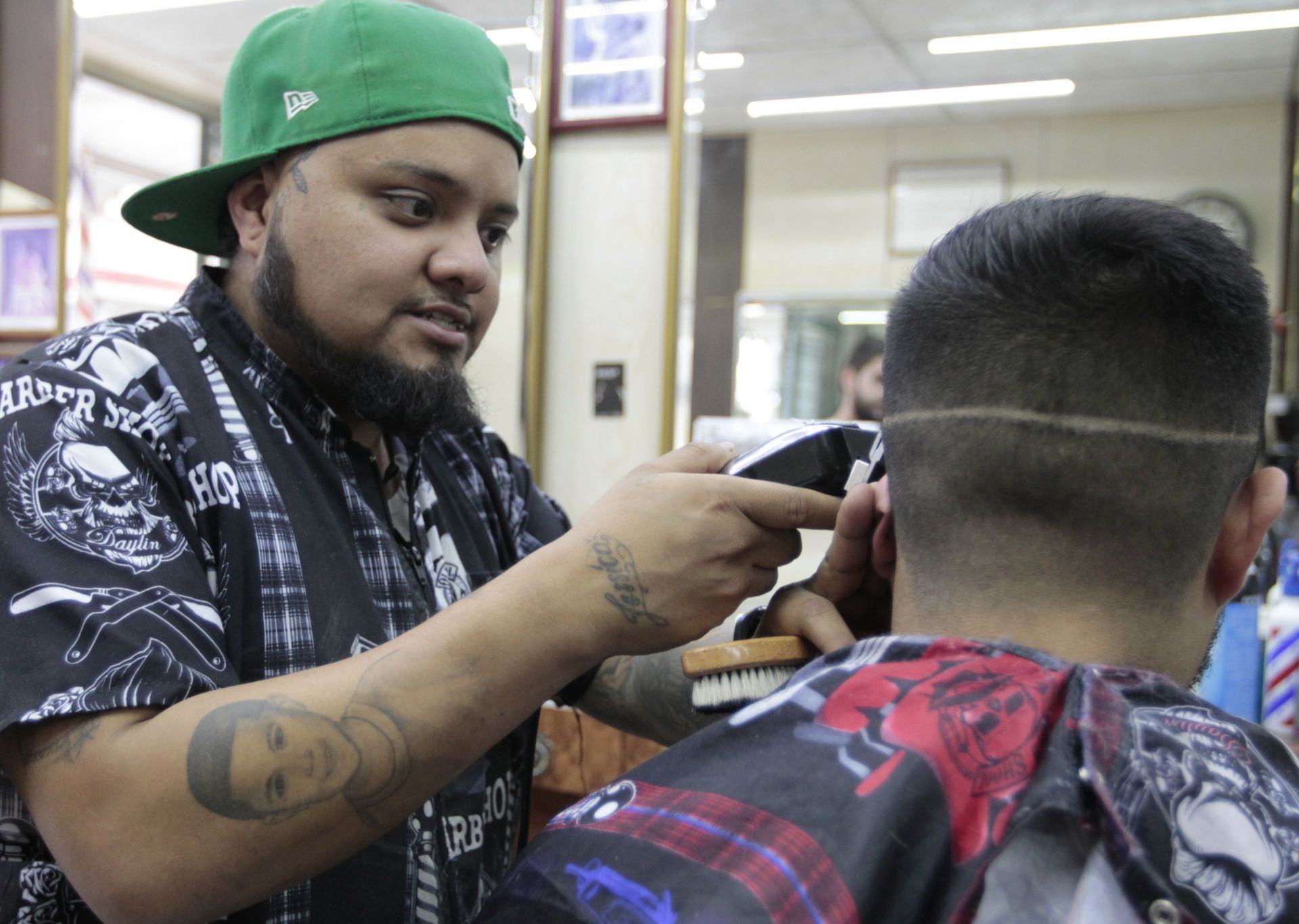 barbero Francisco Hernández (i) mientras corta el pelo a un cliente en una barbería de la colonia Tabacalera
