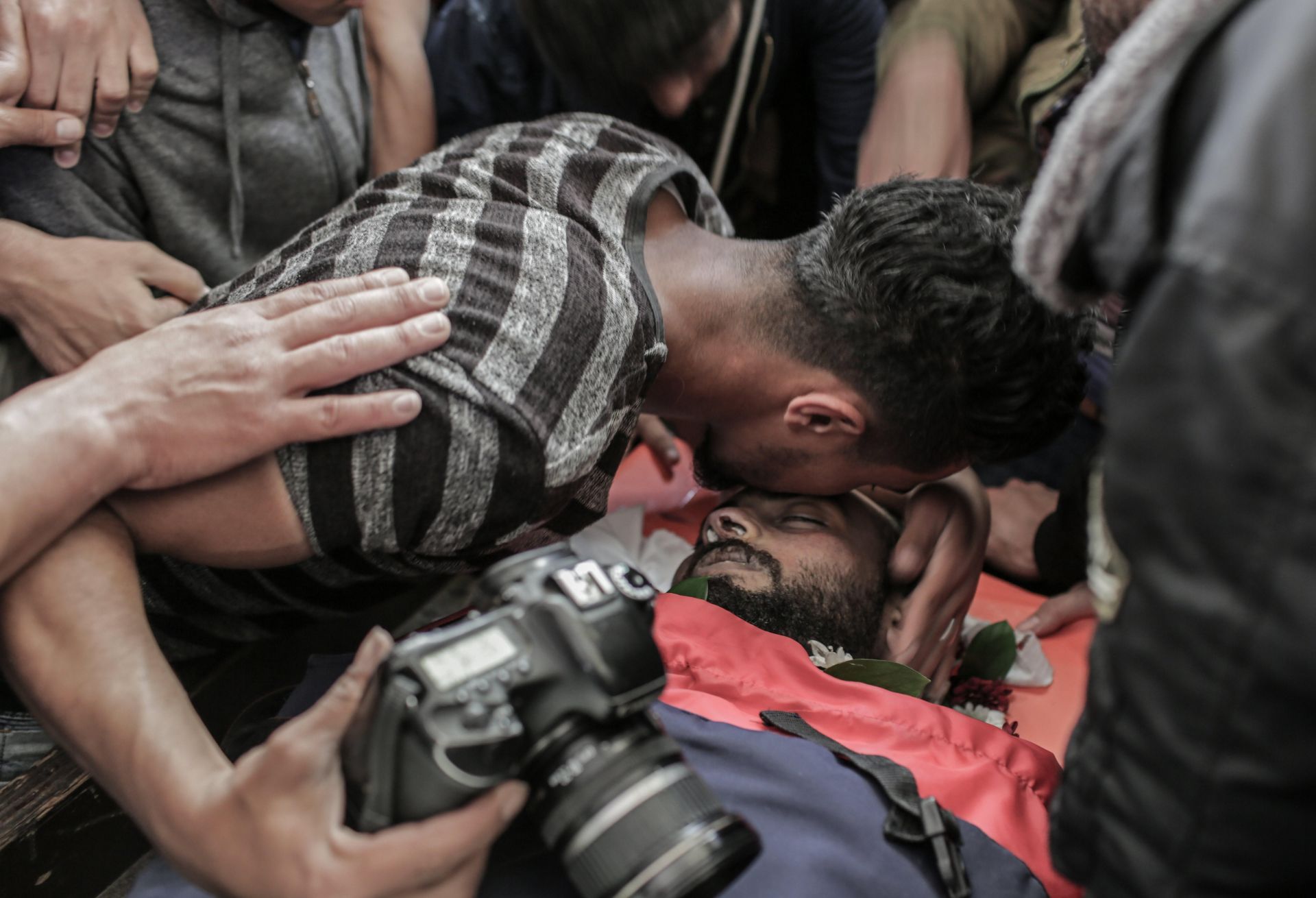 El fotógrafo y amigo del periodista palestimo Ahmad Abu Hussein besa su cuerpo sin vida durante su entierro en el campo de refugiados Jabaliya al norte de la Franja de Gaza.
