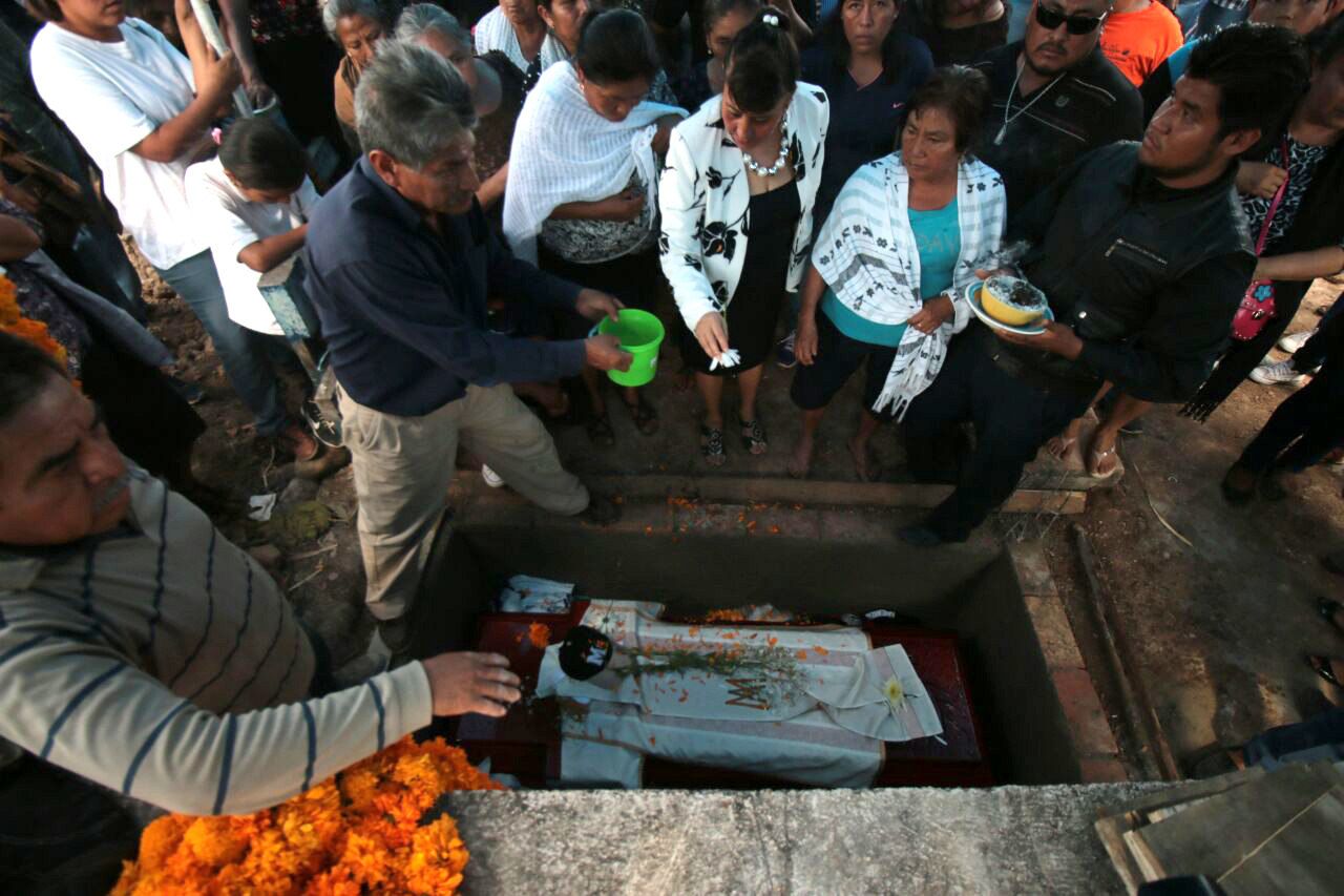  Asistentes ayudan a enterrar el ataúd con los restos del sacerdote Germaín Muñiz García