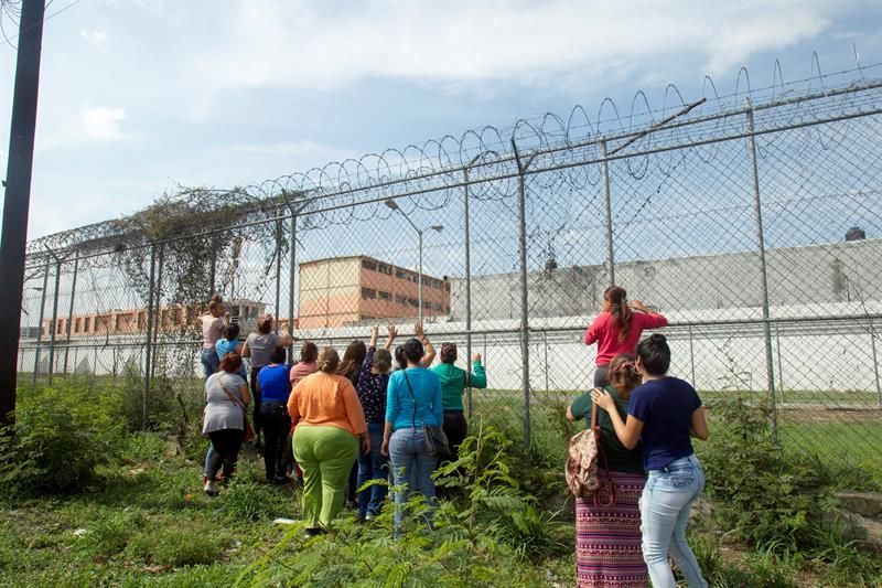 Familiares de internos observan a través de las vallas del penal de Topo Chico para exigir información sobre el traslado de los presos.